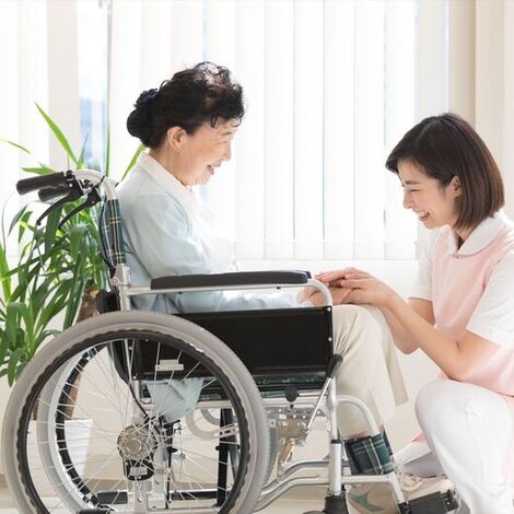 車いすの女性に寄り添う女性ヘルパー